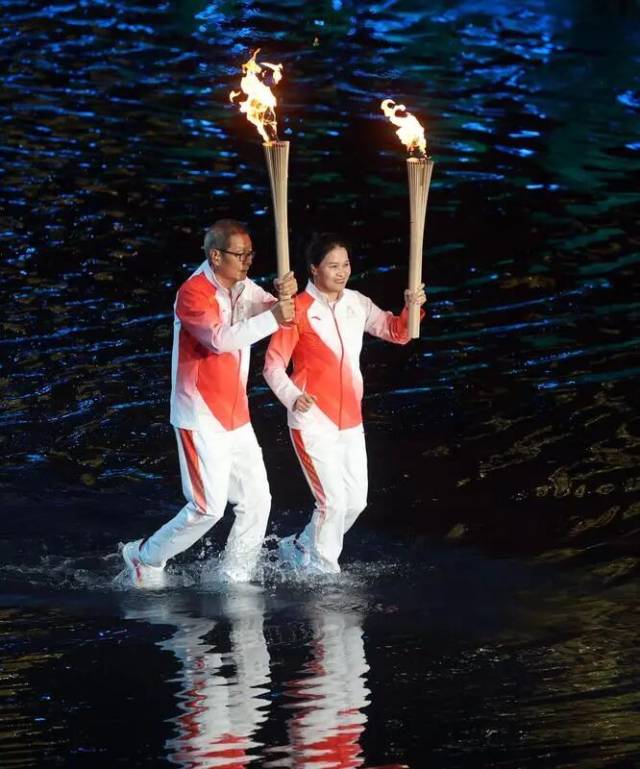 冼东妹（右）在十五运会开幕式传递火炬
